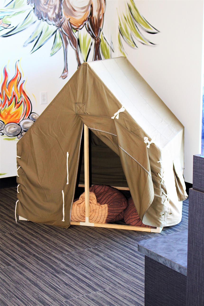 A small tent-like structure with a brown floor inside a room, possibly for children s play or an indoor camping experience.