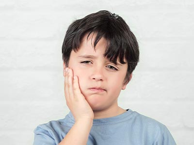 A young boy with his hand on his chin, looking slightly to the side, against a plain background.