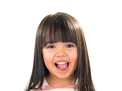 The image shows a young child with long hair smiling at the camera.