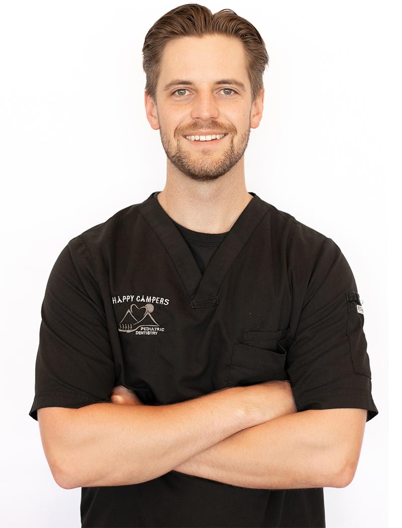 A man wearing a black shirt with white lettering on the front, standing against a white background with his arms crossed.