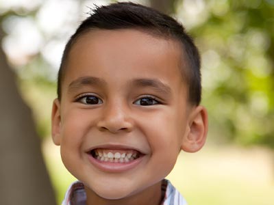 The image shows a young boy with a broad smile, appearing happy and joyful.
