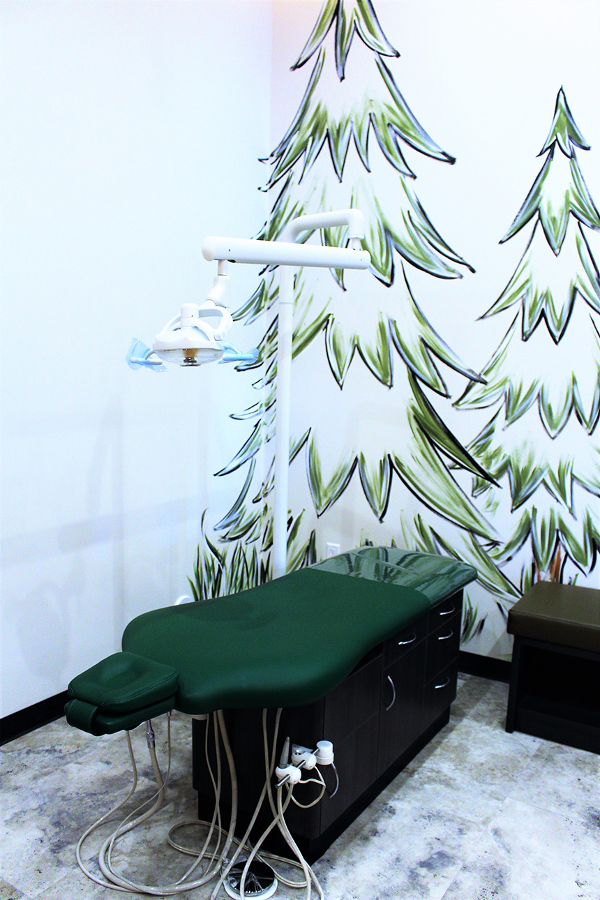 The image shows a dental office with a Christmas tree wallpaper, featuring a dental chair and equipment.
